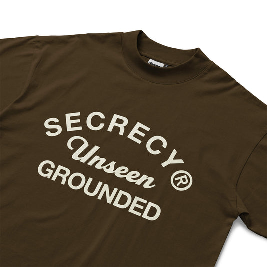 Brown t-shirt with 'Secrecy Unseen Grounded' text on a white background